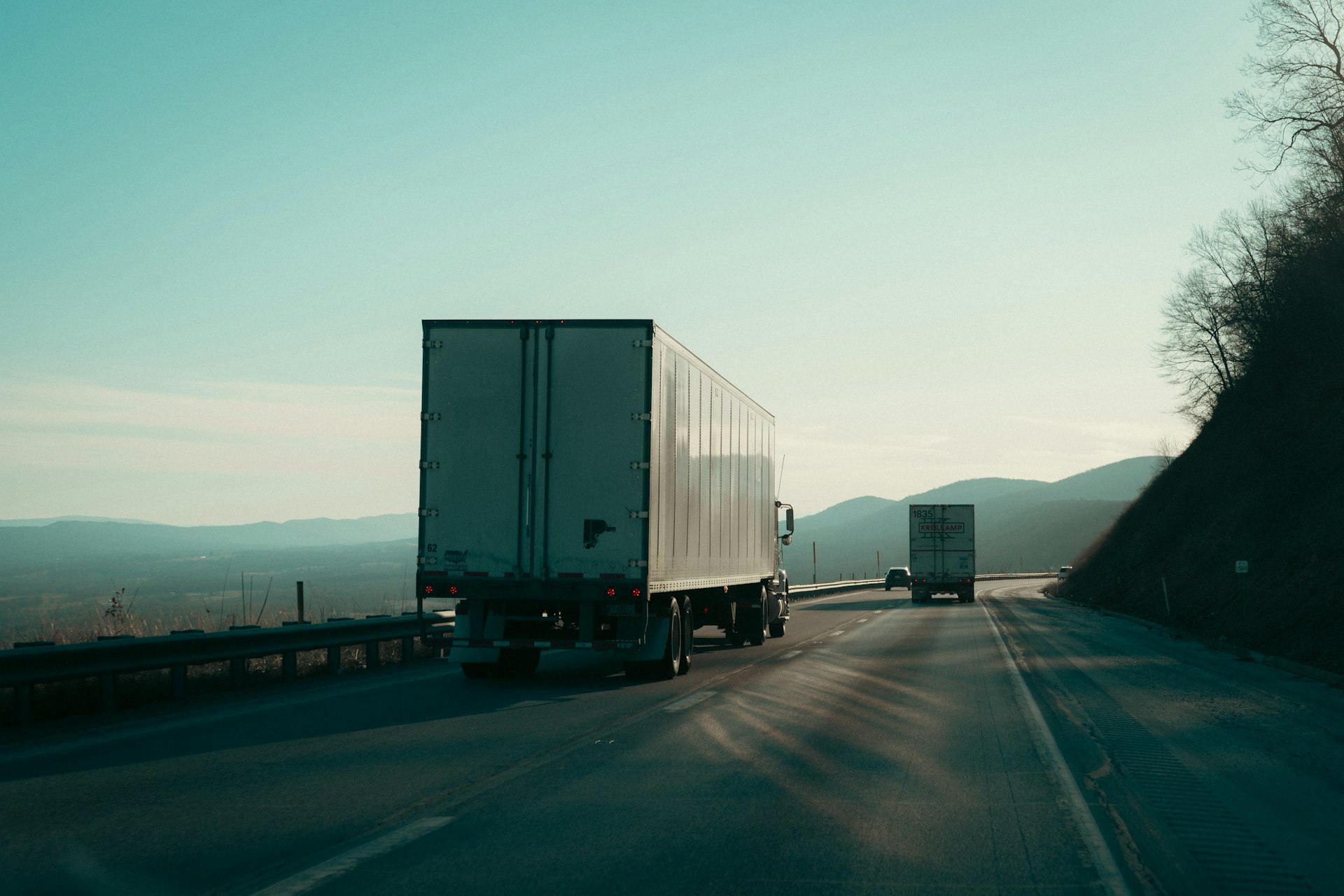 Dry-van tractors running a mountain highway at dusk